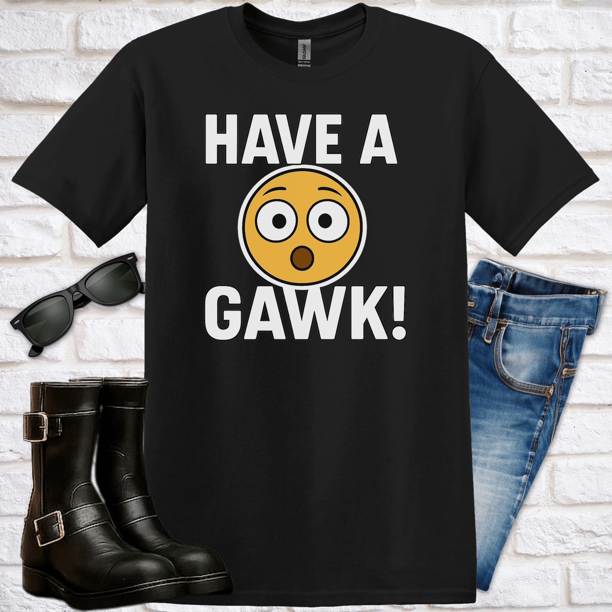 Black t-shirt with 'HAVE A GAWK!' text and emoji, sunglasses, boots, and jeans on a white brick background