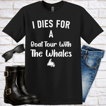 Black t-shirt that says "I dies for a boat tour with the whales" and has a graphic of Newfoundland with, sunglasses, boots, and jeans on a white brick background