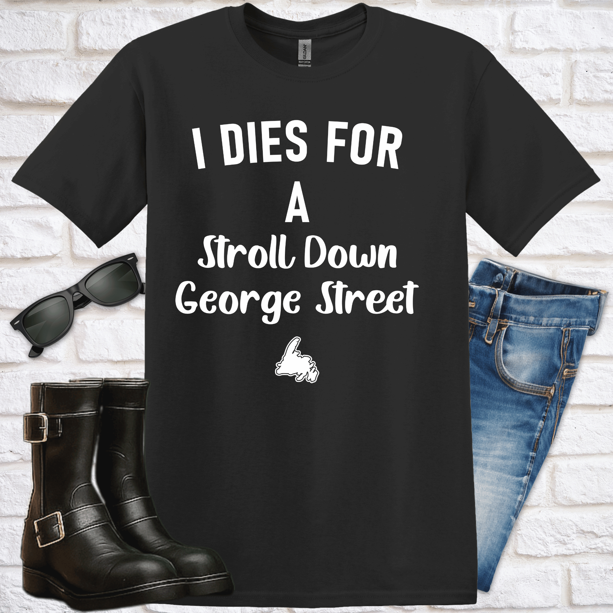 Black t-shirt with text and graphics, sunglasses, boots, and jeans on a white brick background.  The text says "I dies for a stroll down George Street."