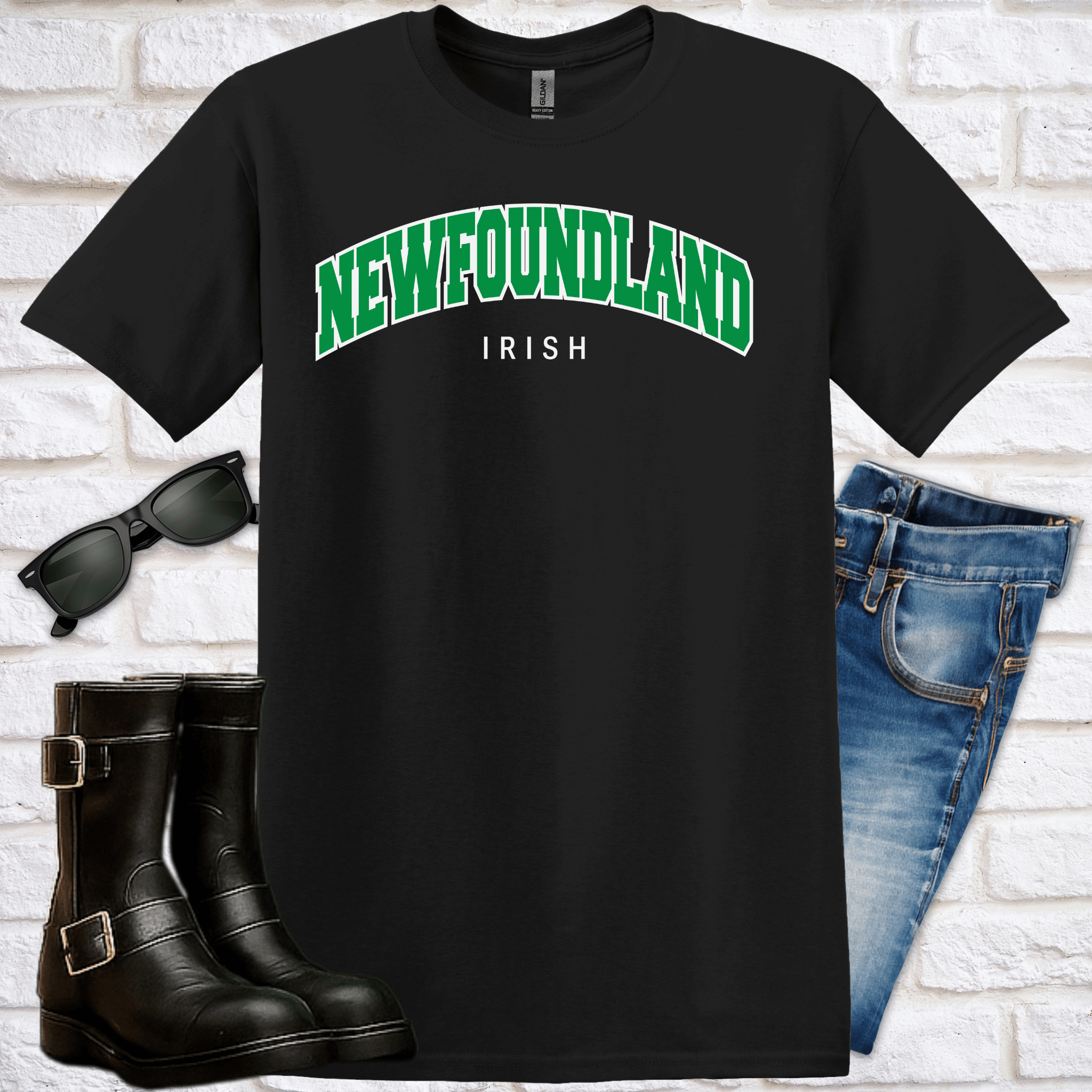 Black t-shirt with 'NEWFOUNDLAND IRISH' text, sunglasses, boots, and jeans on a white brick background