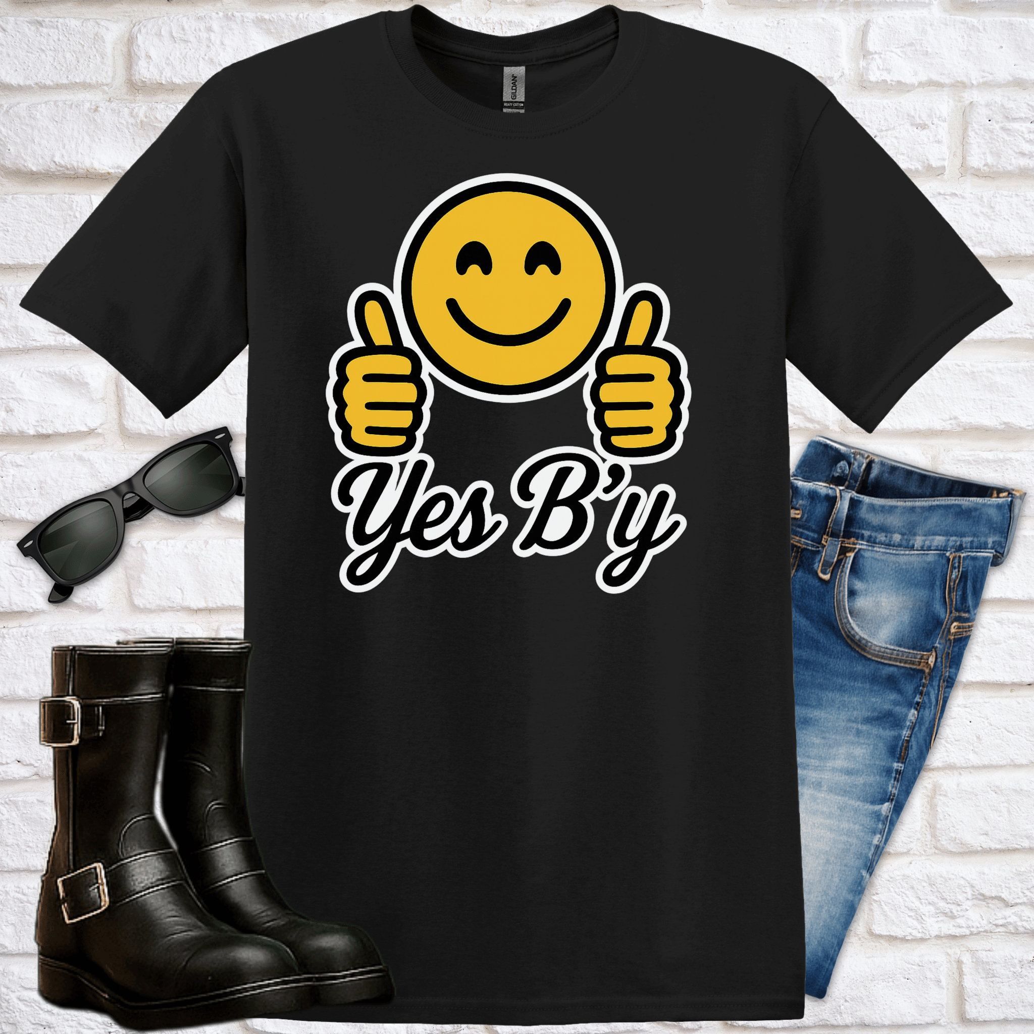 Black t-shirt with smiley face emoji and 'Yes B'y' text, sunglasses, boots, and jeans on a white brick background