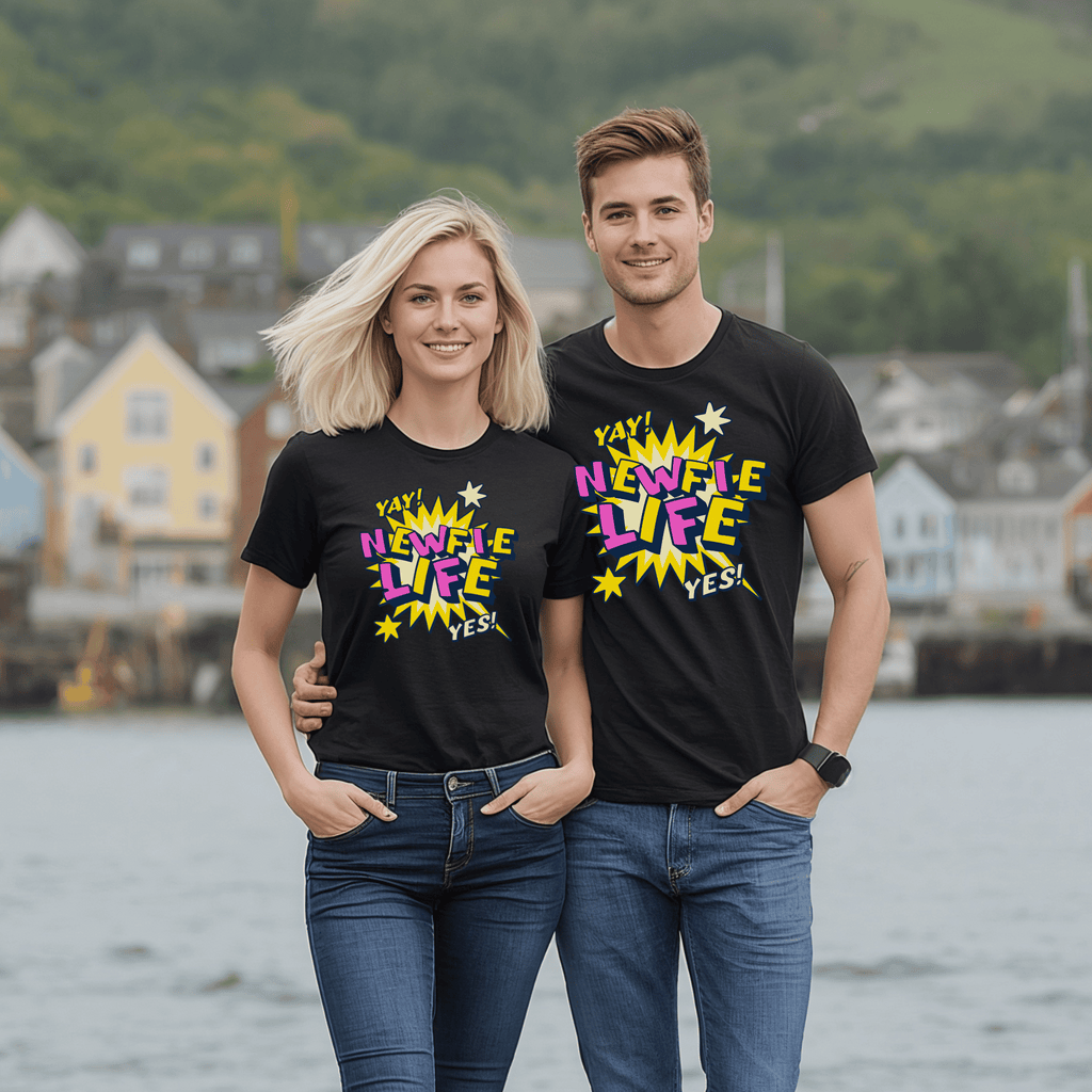 An attractive couple wearing black t-shirts with colorful text saying "Newfie Life" standing by a waterfront.