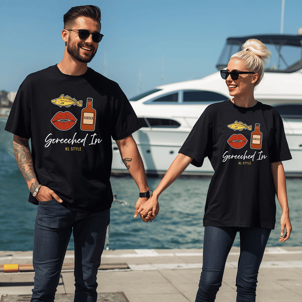 Two people wearing matching black t-shirts with graphic designs of a cod, a mouth and a bottle of screech and text saying "Screeched In--NL Style" standing by a waterfront.