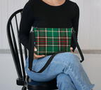 Person holding a Newfoundland and Labrador Tartan Crossbody Purse while sitting on a black chair.