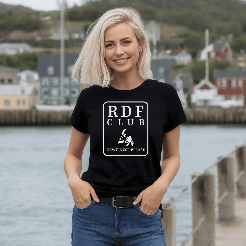 Woman wearing a black t-shirt with 'RDF Club' , a map of Newfoundland, and the Newfinese Please logo design by a waterfront.