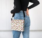 A model wearing a "Screeched In" Crossbody Purse,  featuring a fun pattern of codfish, lipstick kisses, and Screech rum bottles inspired by the iconic island tradition.