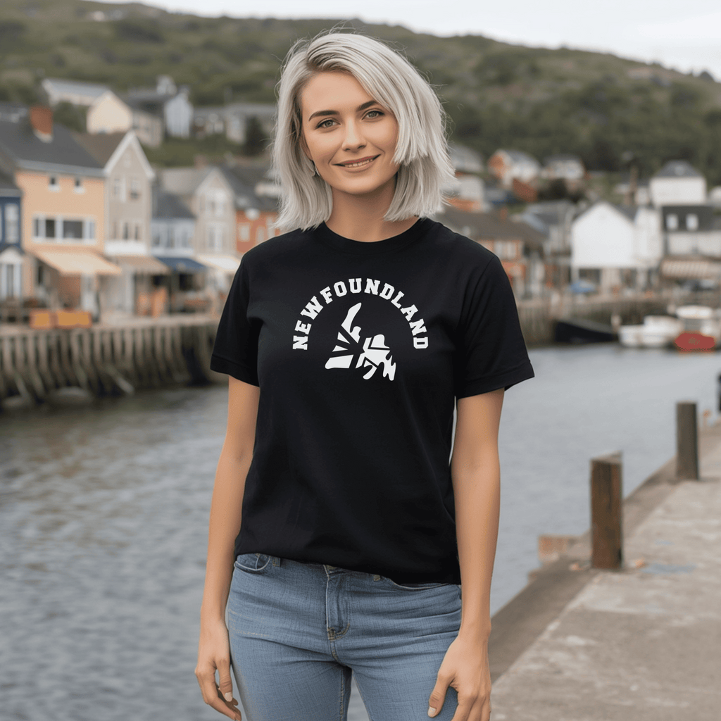 Woman wearing a black t-shirt with 'Newfoundland' design of a map of Newfoundland with curved text of "Newfoundland" above it, by a waterfront.