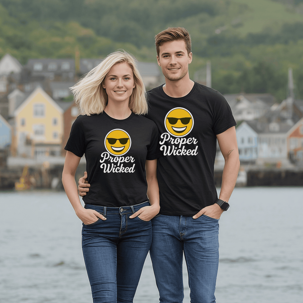 A man and a woman wearing black t-shirts with a smiley face emoji with sunglassed and text saying "Proper Wicked" standing by a waterfront.