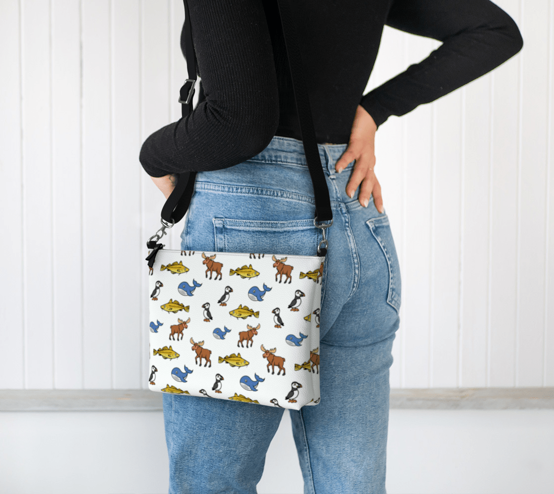 Person wearing a colorful Newfoundland and Labrador animal patterned bag on her hip against a white background