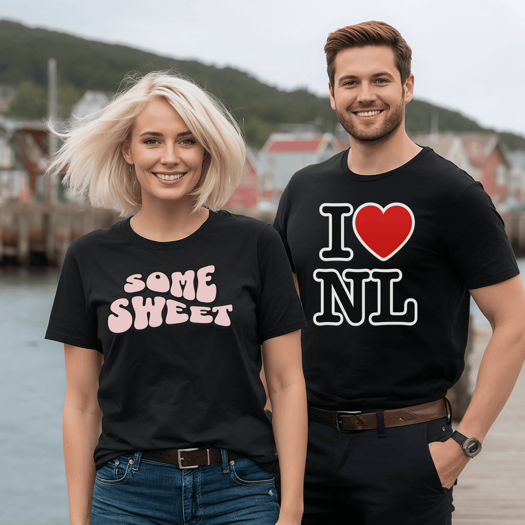 Two attractive people wearing black t-shirts with text, standing outdoors by a body of water. The woman's t-shirt is a retro design with the words "Some Sweet."  The man is wearing our "I heart NL" t-shirt.