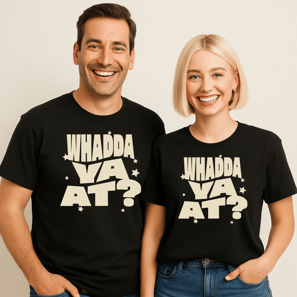 Two attractive people wearing black t-shirts with 'WHADDA YA AT?' text on a beige background