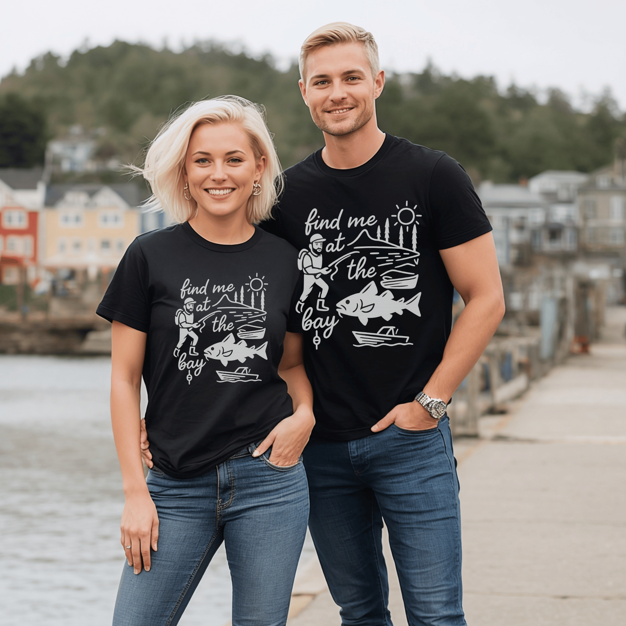Two attractive people wearing matching black t-shirts with a graphic design of a cod, fisherman and boat and the text, "find me at the bay."