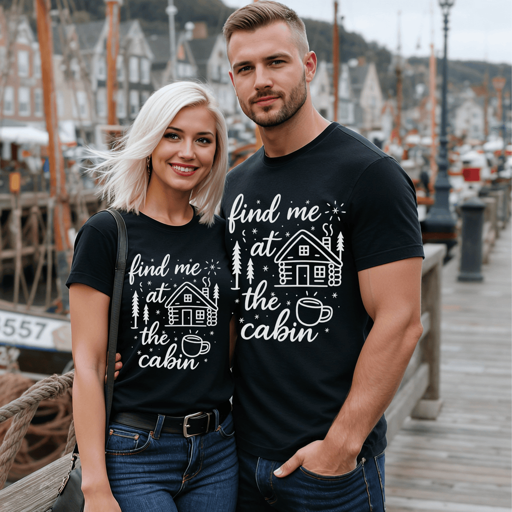 Attractive couple wearing matching black t-shirts with a cabin-themed design with the words "find me at the cabin."