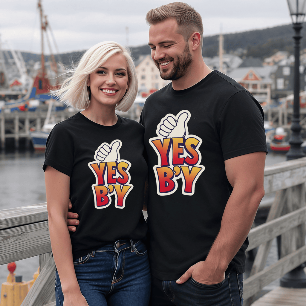 An attractive couple wearing black t-shirts with text 'YES B'Y' and thumbs up design in a harbor setting.