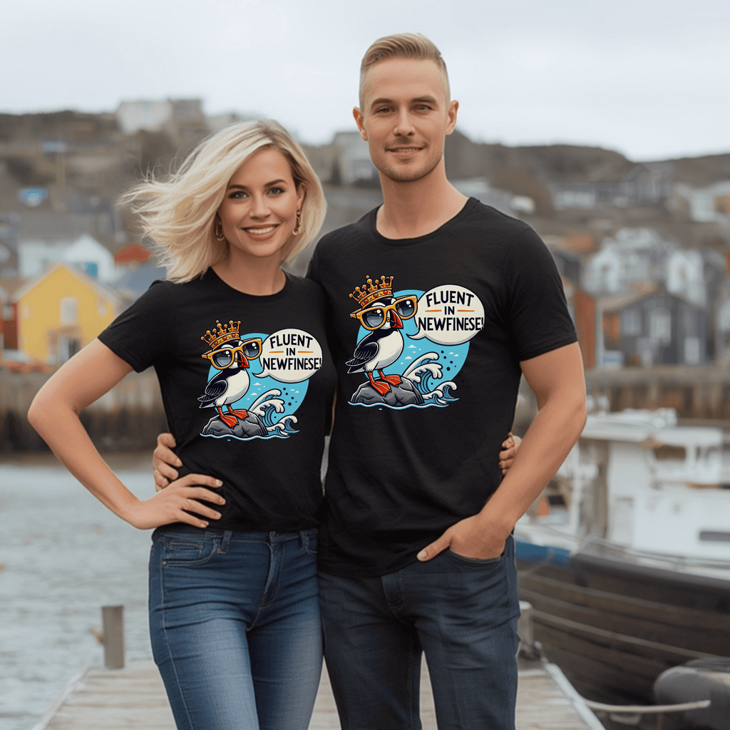 Two attractive people wearing matching black t-shirts with a cartoon puffin adorning a crown and the words "Fluent in Newfinese!"  on a dock.