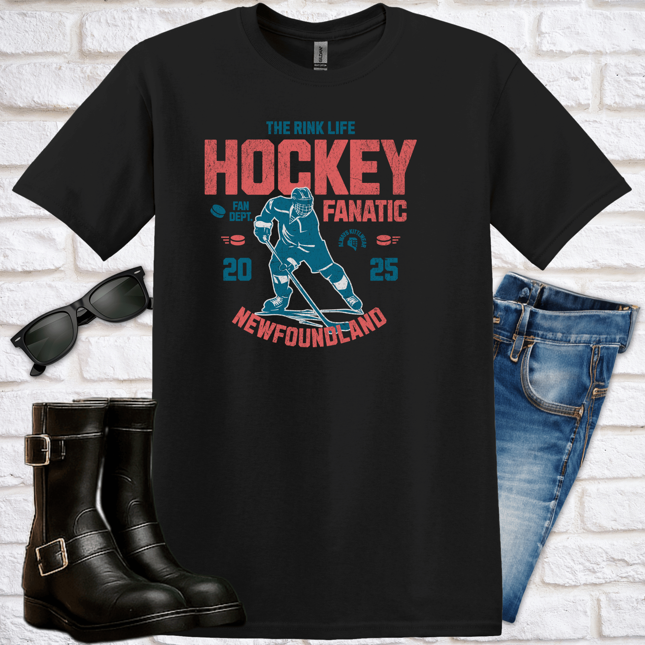 Black t-shirt with hockey graphic and text saying Hockey Fanatic, Newfoundland, with sunglasses, boots, and jeans on a white brick background