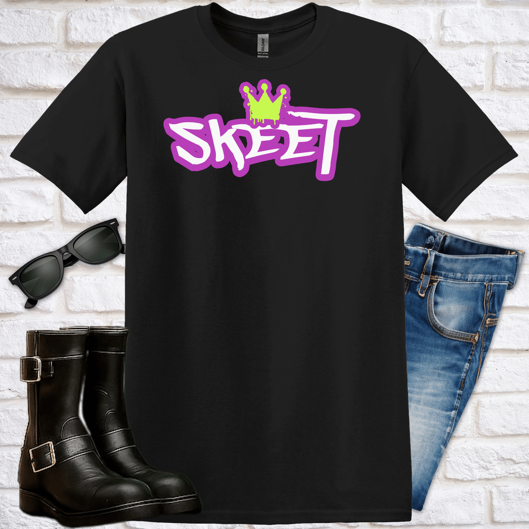 Black t-shirt with 'SKEET' logo with crown, with sunglasses, black boots, and blue jeans on a white brick background