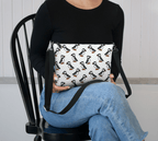 A Crossbody Purse with a pattern of puffins on the lap of a model.